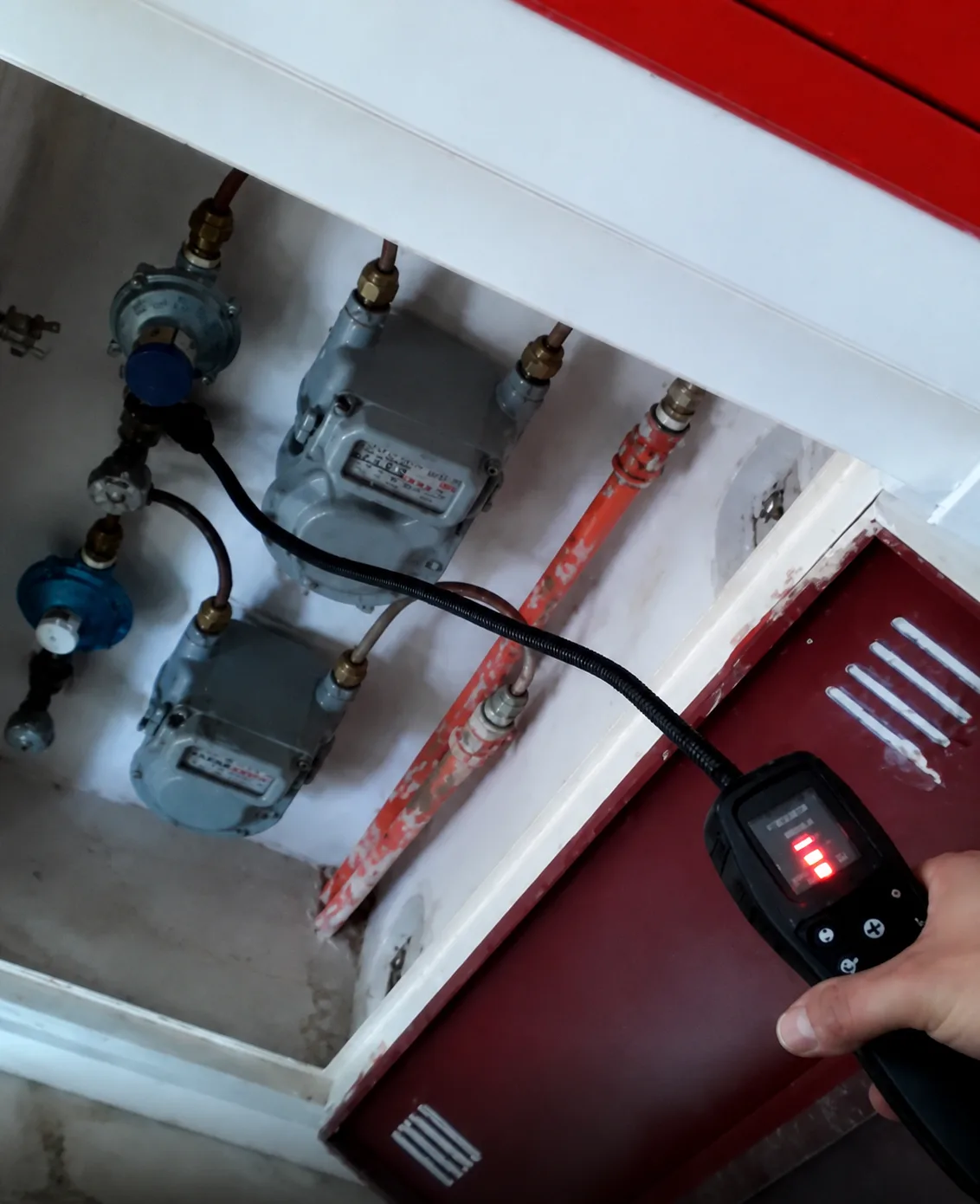 Técnico utilizando detector eletrônico em central de medidores de gás